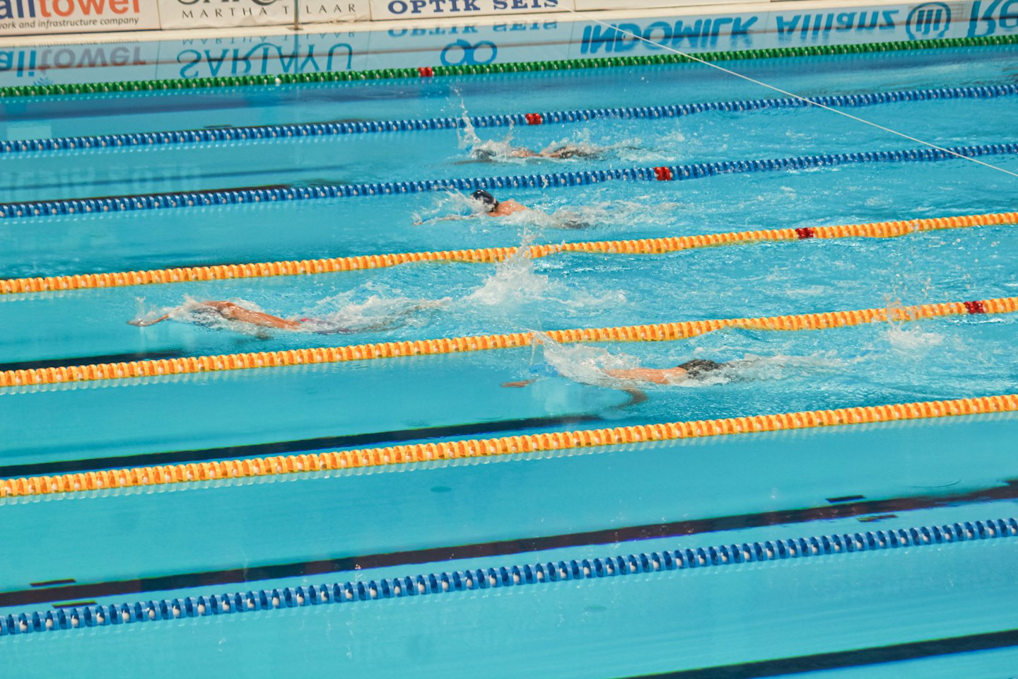 Des nageurs font la course en nage libre dans les couloirs d'une piscine intérieure.